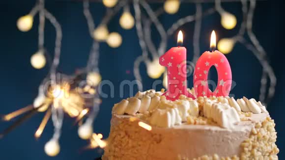 生日蛋糕10个数字燃烧粉红色蜡烛和闪闪发光的蓝色背景慢速运动和特写镜头视频的预览图