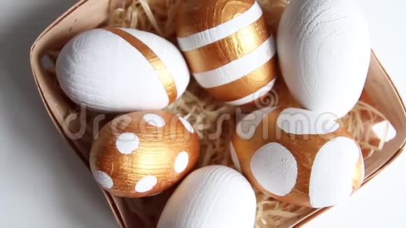 桌上放着金色和白色的鸡蛋闪亮的糖果掉了下来节日庆典录像复活节快乐视频的预览图