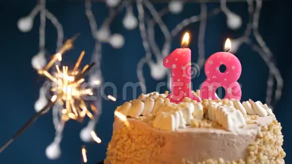 生日蛋糕与18号燃烧粉红色蜡烛和闪闪发光的蓝色背景慢速运动和特写镜头视频的预览图