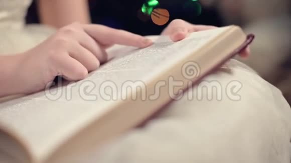 一个身穿节日礼服手里拿着一本书的金发小女孩坐在背景软玩具旁边视频的预览图