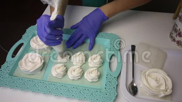 托盘上摆着一个玫瑰形的棉花糖一个女人在糕点袋的帮助下形成了一个经典形状的棉花糖视频的预览图