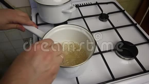 一个拿着铲子的人把煮好的糖浆混合成棉花糖煤气炉上的砂锅里的糖浆视频的预览图