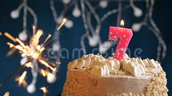 生日蛋糕与7号燃烧粉红色蜡烛和闪闪发光的蓝色背景慢速运动和特写镜头视频的预览图