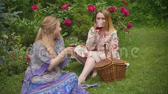 美丽优雅的女人喝着红酒享受着在美丽的夏日花园里盛开牡丹的假期视频的预览图