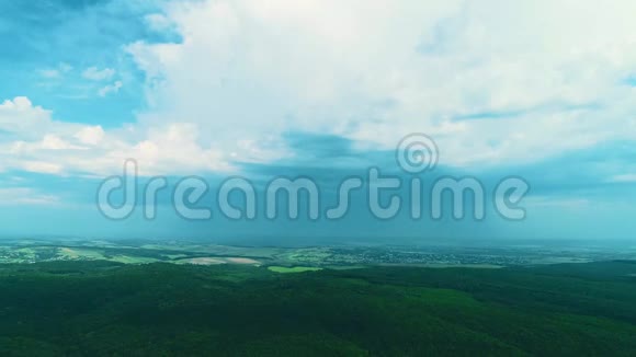 空中无人驾驶飞机观看生长在山丘上的绿色密林美丽的村庄景观和白云的蓝天视频的预览图