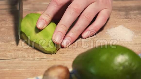 女性用菜刀将成熟的鳄梨切成薄片在木桌上做鳄梨酱特写视频的预览图