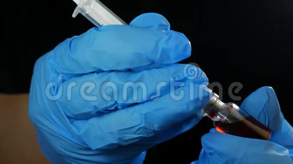 医生手拿着注射器和一个红色疫苗瓶在医院的黑色背景卫生和医疗视频的预览图