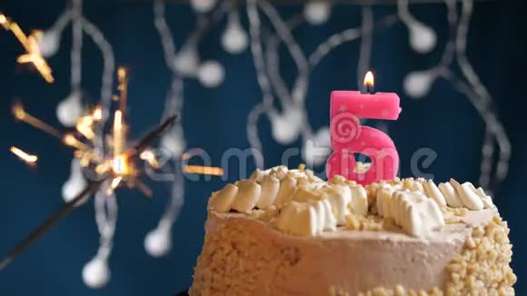 生日蛋糕与5号燃烧粉红色蜡烛和闪闪发光的蓝色背景慢速运动和特写镜头视频的预览图