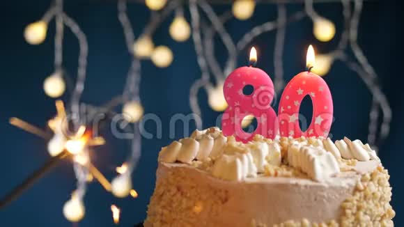生日蛋糕与80号燃烧粉红色蜡烛和闪闪发光的蓝色背景慢速运动和特写镜头视频的预览图