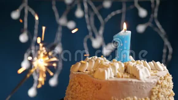 生日蛋糕与1号燃烧蓝色蜡烛和闪闪发光的蓝色背景慢速运动和特写镜头视频的预览图