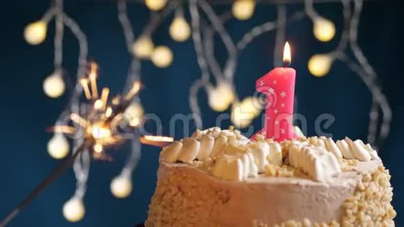 生日蛋糕与1号燃烧粉红色蜡烛和闪闪发光的蓝色背景慢速运动和特写镜头视频的预览图