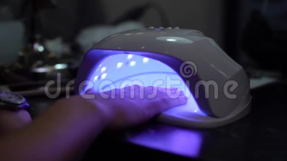 在美甲美容店的紫外线灯里女人用紫胶擦指甲视频的预览图