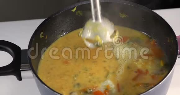 一个女人把成品奶油汤和一个手搅拌锅里的搅拌器混合在一起健康饮食观念视频的预览图