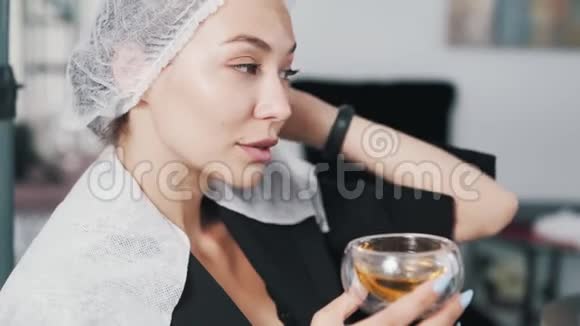 美容帽上的美女在美容院喝茶做头发护理视频的预览图
