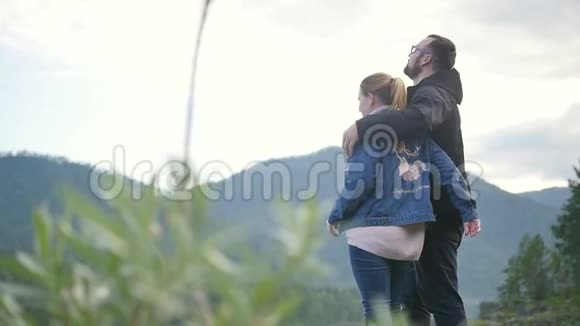 一对年轻的恋人拥抱在阿尔泰山和山河的背景上慢动作视频的预览图