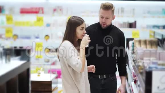 夫妻二人在化妆品店里选择香水女人打开闻一闻视频的预览图