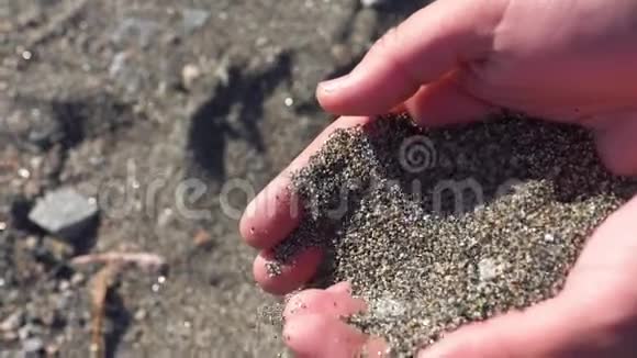女孩在海滩上用手倒沙子慢动作视频的预览图