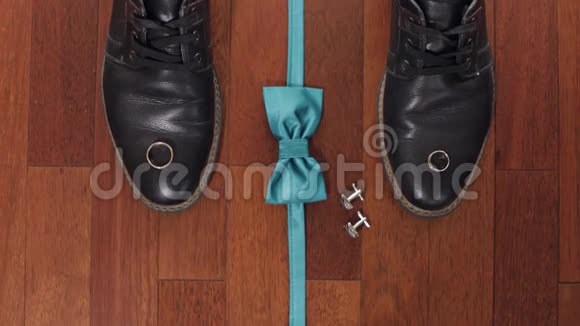 结婚戒指绿色新郎领结袖扣和棕色木地板上的鞋子视频的预览图