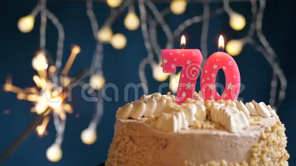 生日蛋糕70个数字燃烧粉红色蜡烛和闪闪发光的蓝色背景慢速运动和特写镜头视频的预览图