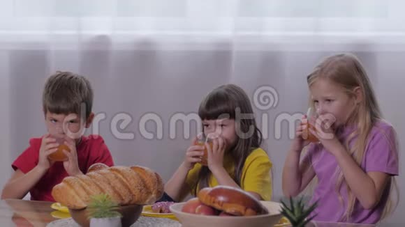 甜蜜的桌子有趣的孩子咬一口喝果汁后积极的游戏以庆祝孩子的聚会视频的预览图