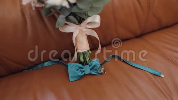 漂亮的结婚花束躺在沙发上戴着结婚戒指和新郎的领结视频的预览图