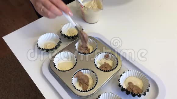 一个女人把有可可的面团放在松饼烤盘里做大理石蛋糕视频的预览图
