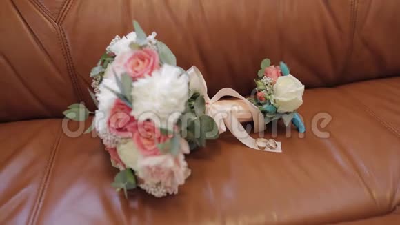 美丽的婚礼花束躺在棕色沙发上戴着结婚戒指视频的预览图