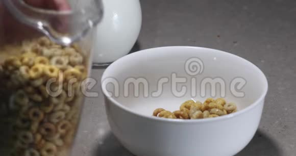 健康的早餐一个女人从透明的盒子里把玉米片倒进一个白色的碗里视频的预览图