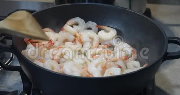 一个女人用辣椒和大蒜将炸虾搅入锅中视频的预览图