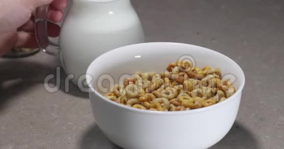 健康的早餐一个女人把牛奶倒入一个盛着玉米片的杯子里视频的预览图