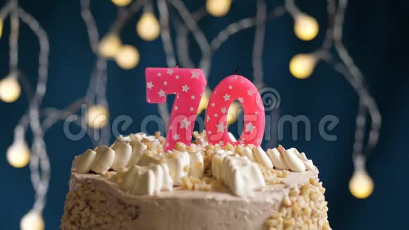 生日蛋糕70个数字燃烧由较轻的粉红色蜡烛在蓝色的背景蜡烛被点燃了慢动作视频的预览图