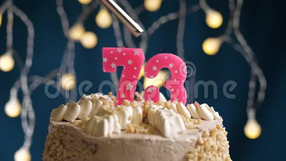 生日蛋糕有73个数字由较轻的粉红色蜡烛燃烧在蓝色的背景上蜡烛被点燃了慢动作视频的预览图