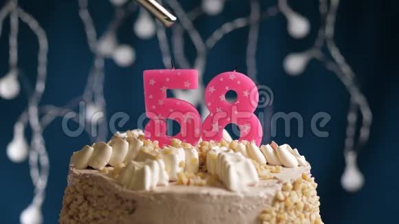 生日蛋糕有58个数字用较轻的粉红色蜡烛在蓝色的背景上燃烧蜡烛被点燃了慢动作视频的预览图