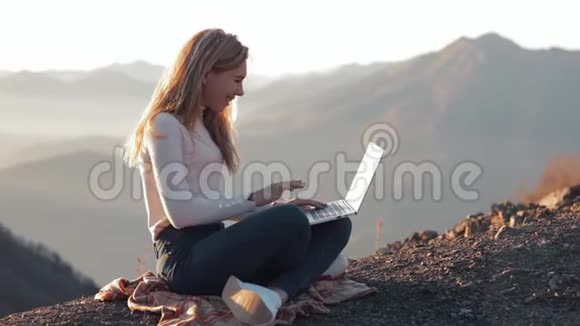 女孩子在笔记本电脑上聊天欣赏美丽的山景视频的预览图