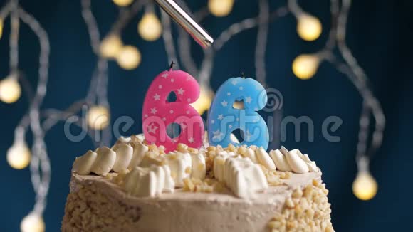 生日蛋糕有66个数字由较轻的粉红色蜡烛燃烧在蓝色的背景上蜡烛被点燃了慢动作视频的预览图