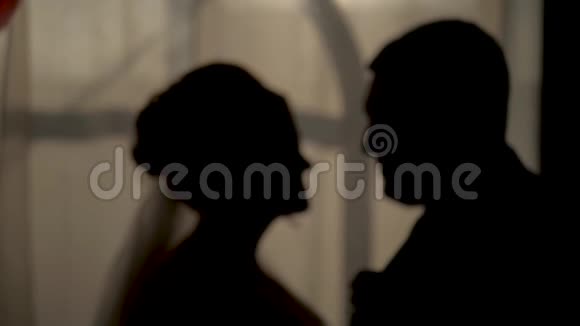 新娘和新郎亲吻浪漫的背景下日落窗口剪影拍摄特写和慢动作视频的预览图