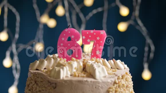 生日蛋糕有67个数字由较轻的粉红色蜡烛燃烧在蓝色的背景上蜡烛被点燃了慢动作视频的预览图