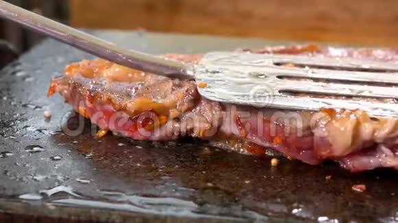 美味的肉排用金属刮刀压在石架上视频的预览图