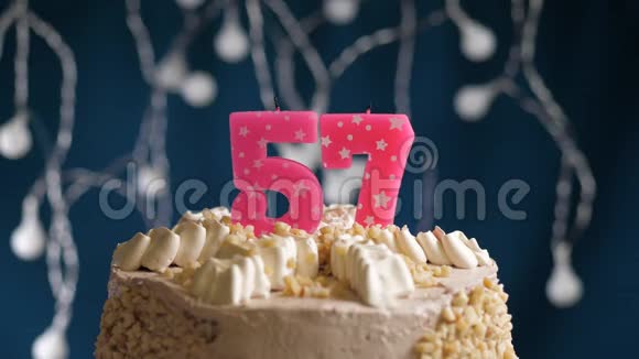 生日蛋糕有57个数字由较轻的粉红色蜡烛燃烧在蓝色的背景上蜡烛被点燃了慢动作视频的预览图