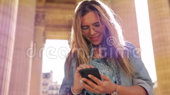 穿着智能手机与朋友聊天的万神殿卫城专栏中迷人的微笑女孩画像视频的预览图