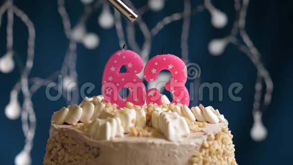 生日蛋糕有63个数字由较轻的粉红色蜡烛燃烧在蓝色的背景上蜡烛被点燃了慢动作视频的预览图