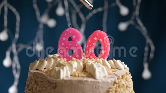 生日蛋糕有60个数字由较轻的粉红色蜡烛燃烧在蓝色的背景上蜡烛被点燃了慢动作视频的预览图
