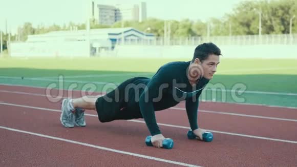 肌肉男做俯卧撑运动与哑铃在交叉适合的锻炼4K视频的预览图