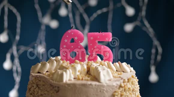 生日蛋糕有65个数字由较轻的粉红色蜡烛燃烧在蓝色的背景上蜡烛被点燃了慢动作视频的预览图