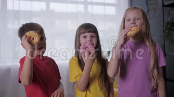 有趣的小朋友站在手里拿着甜甜圈一边吃零食在儿童聚会上玩了半个活跃的游戏视频的预览图