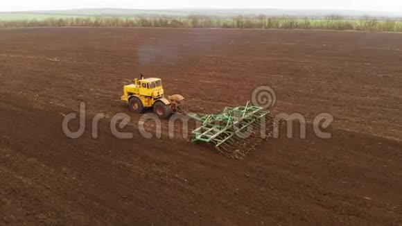 一辆黄色拖拉机的鸟瞰图拖车在种植谷物之前在耕地上犁地这就是视频的预览图