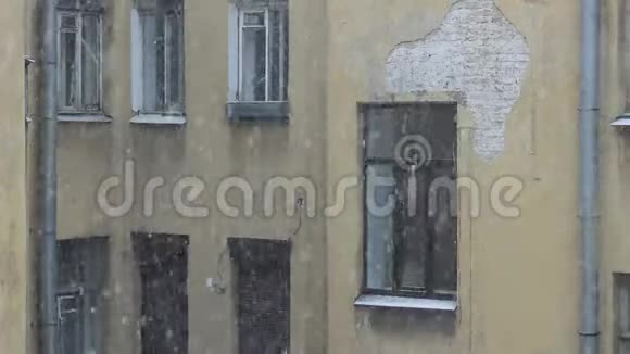 一座有窗户的黄色老房子的背景下冬天降下了大雪视频的预览图