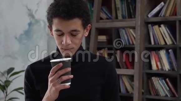 一个年轻人独自在图书馆喝着咖啡微笑着快乐着视频的预览图