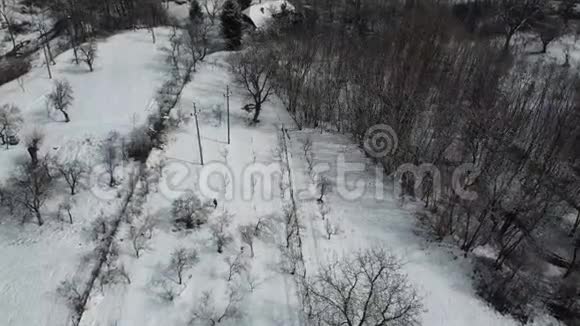 一位在雪地上行走的老妇人的空中射击视频的预览图