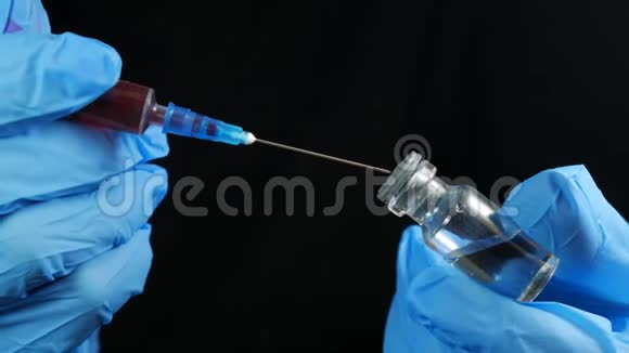 医生手拿着注射器和一个红色疫苗瓶在医院的黑色背景卫生和医疗视频的预览图